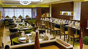 Un restaurante moderno con varias áreas de comedor, incluyendo un bar y un espacio de estar con techos altos y decoración contemporánea.