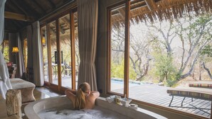 A large stone bathtub with a view of trees outside.