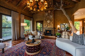 Un salón amplio con chimenea, ventanas grandes y una araña.