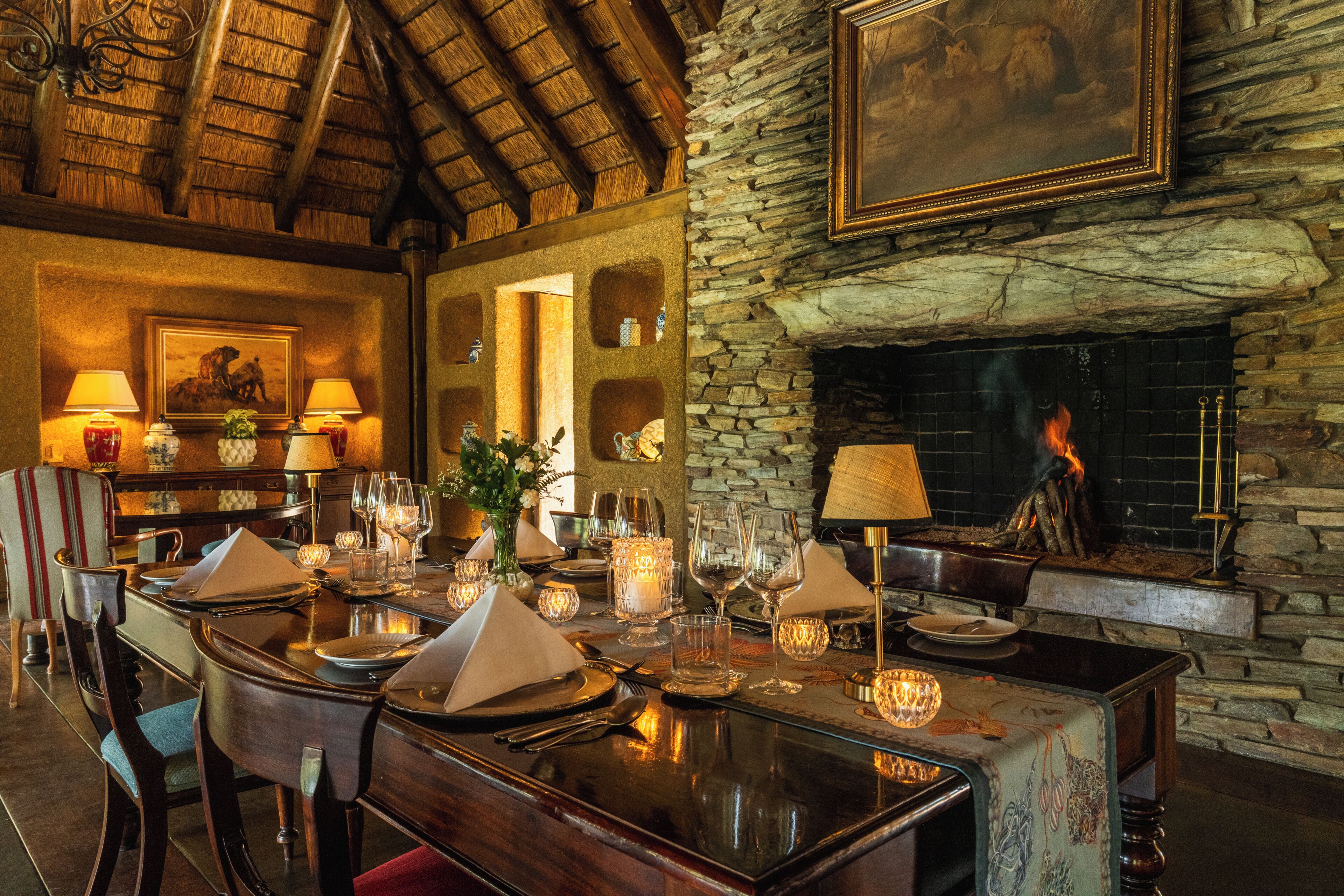 A dining area with a stone fireplace, wooden ceiling, and a table set for a meal.