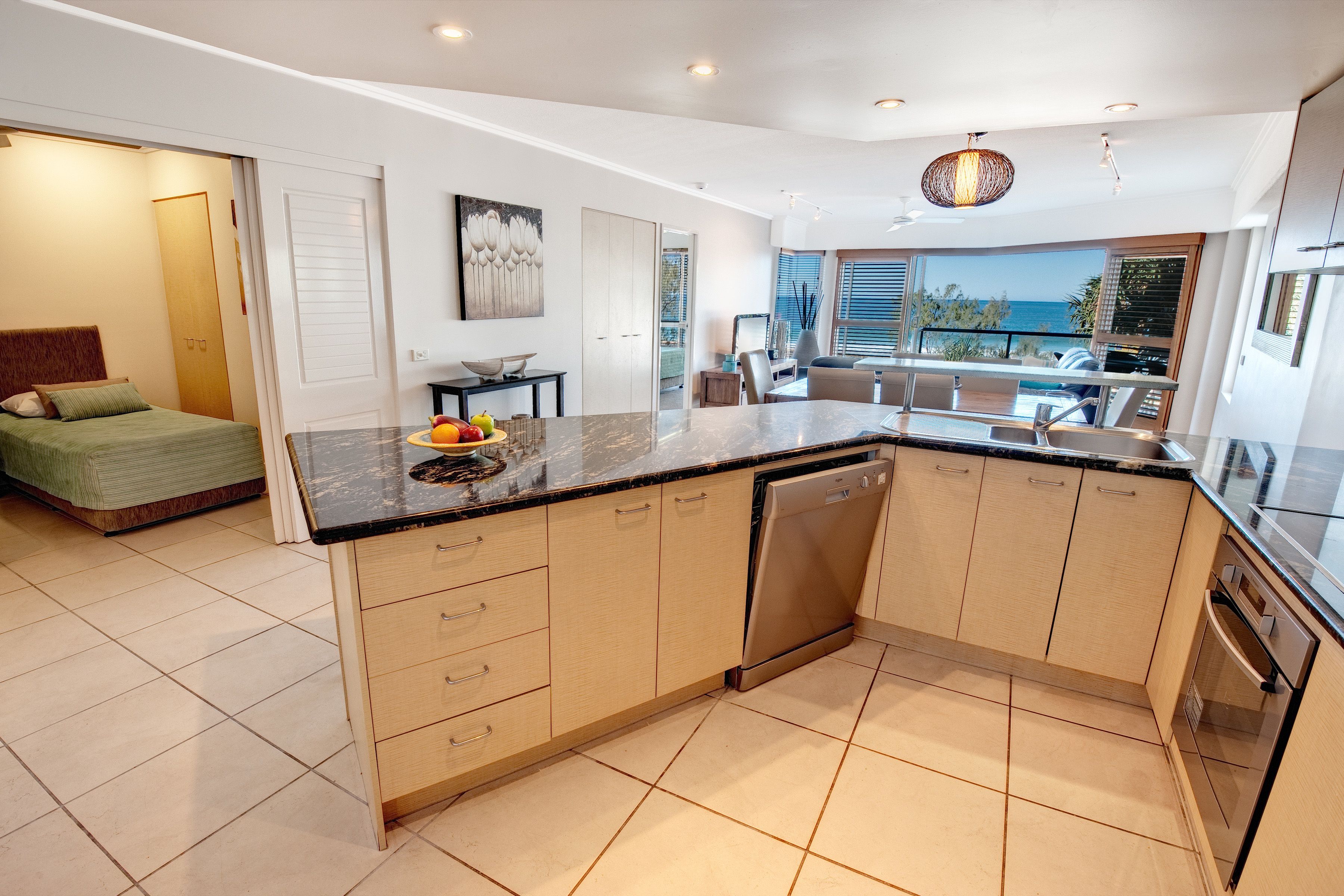 A modern kitchen with a large island, built-in appliances, and a view of the sea.
