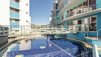 A swimming pool with a tiled deck and a glass barrier.