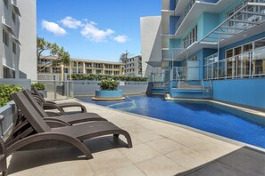 Una piscina al aire libre, sillones reclinables de piscina