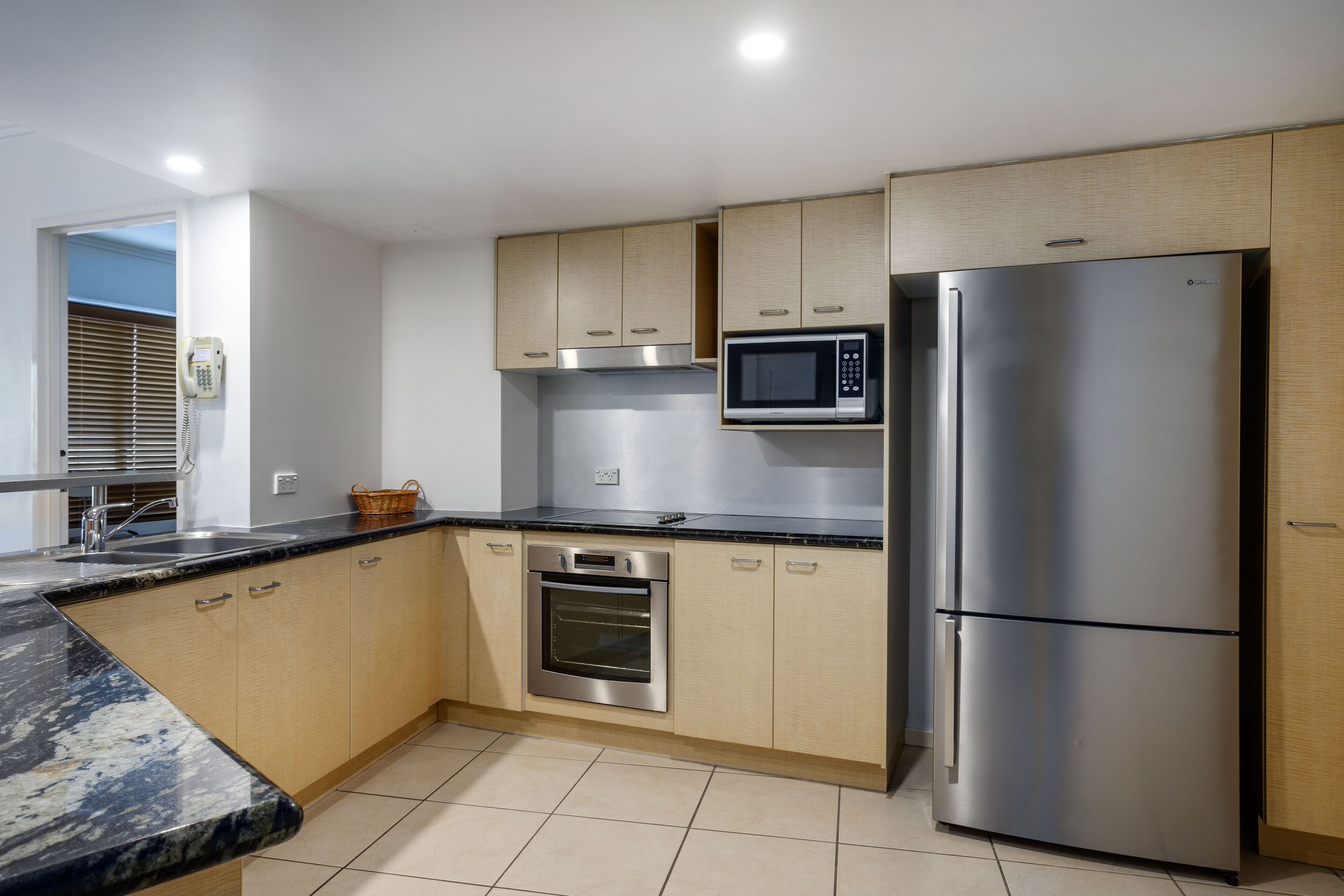 Una cocina moderna con armarios de madera, un refrigerador de acero inoxidable, un microondas y un horno.