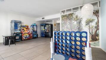 Relax and play in this vibrant space, featuring a large play area, arcade machines, and a tropical mural.