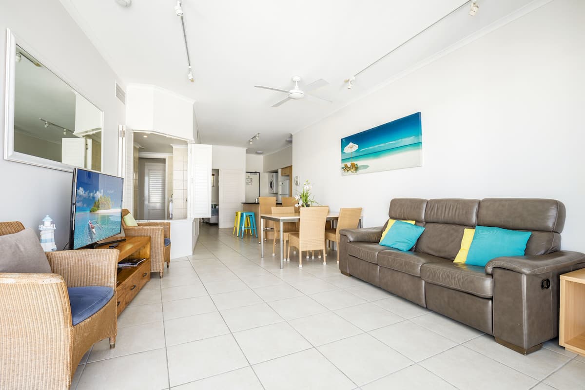 A living room with a sofa, chairs, a TV, and a dining area with a table and chairs.