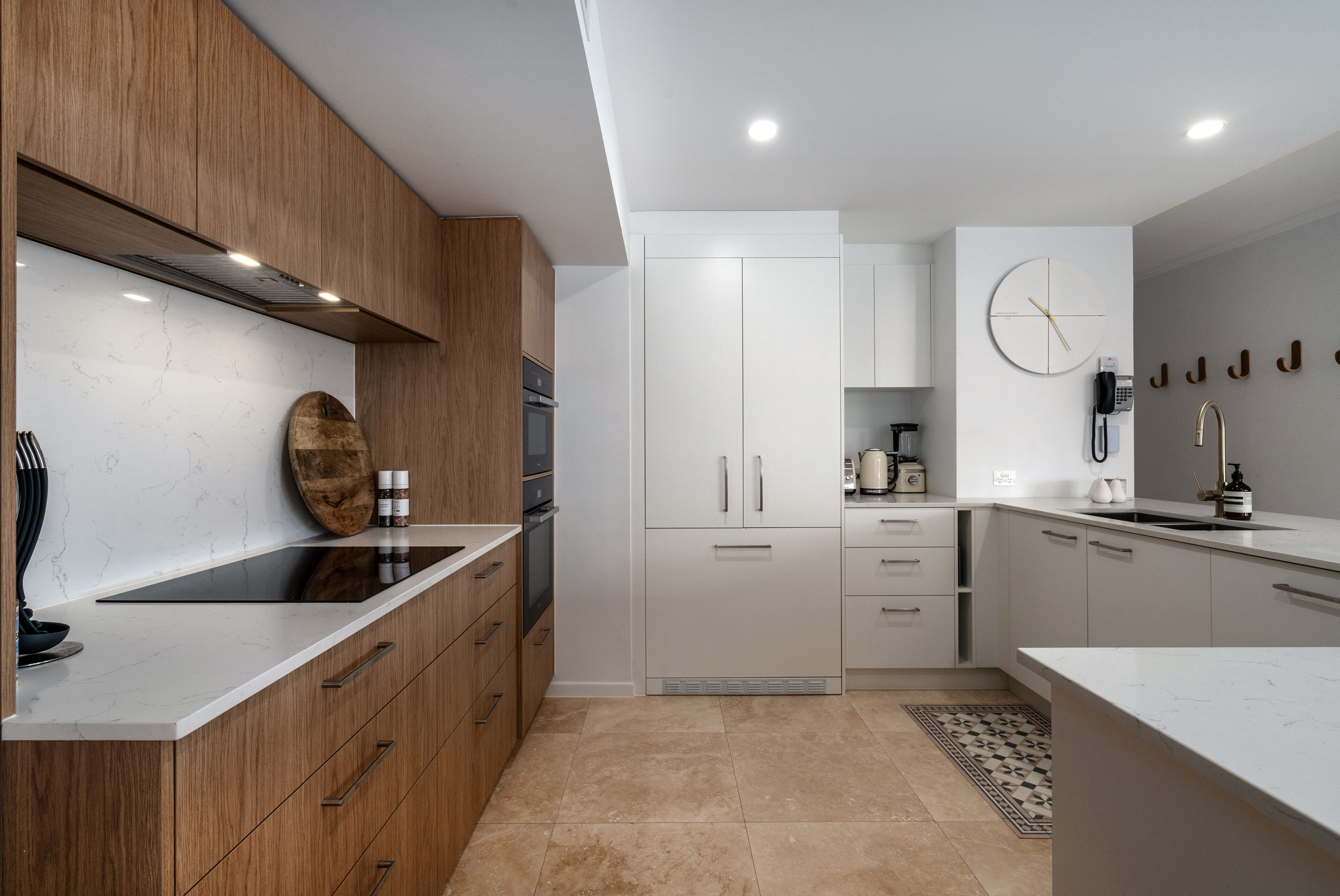 A modern kitchen with wooden cabinets, a white countertop, and a built-in oven.