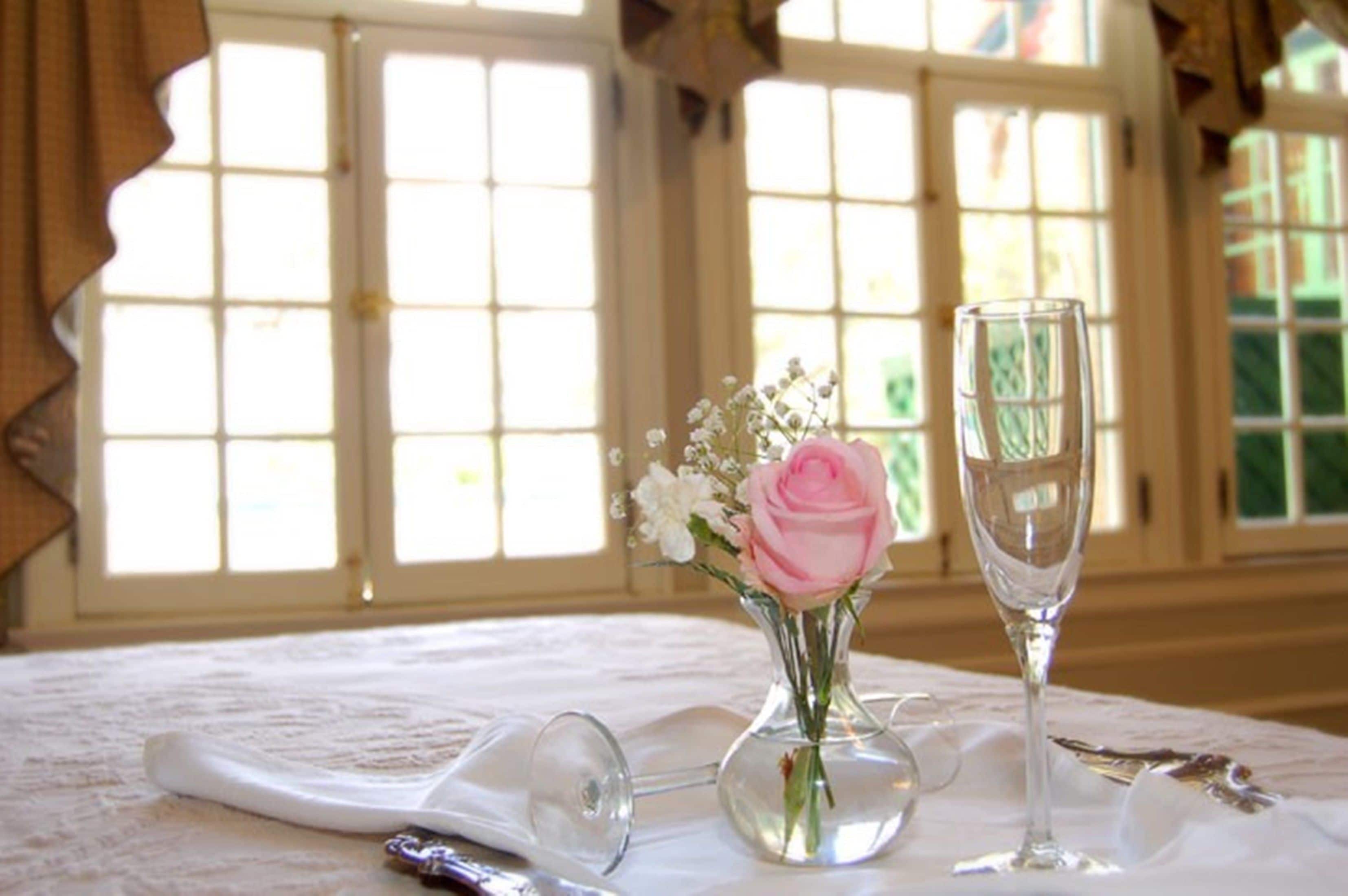 A table with a vase of flowers and a wine glass.