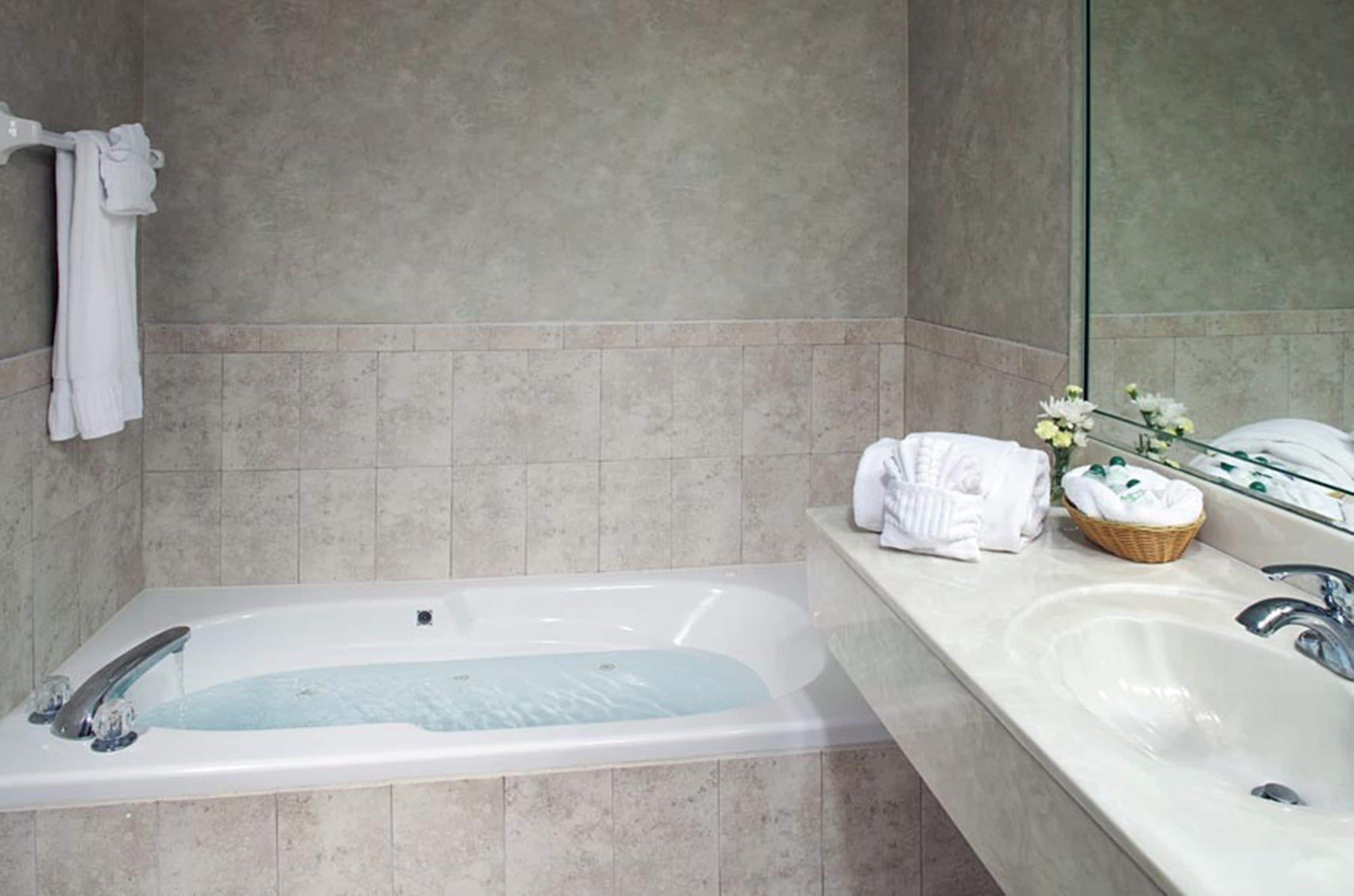 A modern bathroom with a bathtub, a sink, and a mirror.