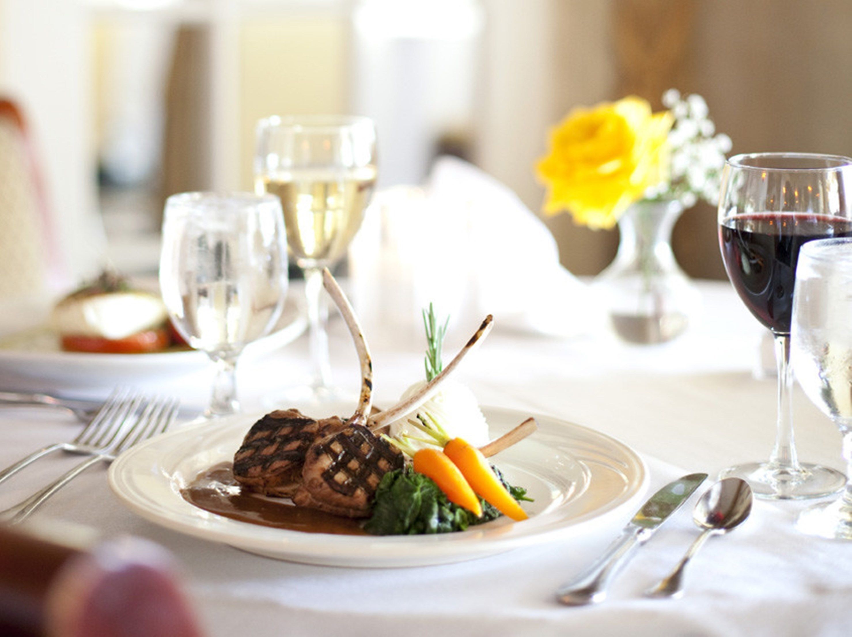 Une table à manger joliment dressée, avec une assiette de nourriture, des verres à vin et des couverts.