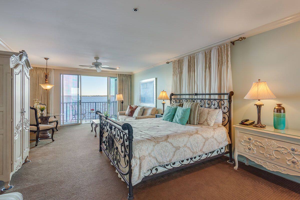 A spacious bedroom with a large bed, a balcony with a view, and a classic design.
