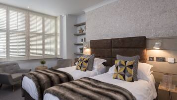 A bedroom with two beds, a sofa, a small table, and a nightstand.