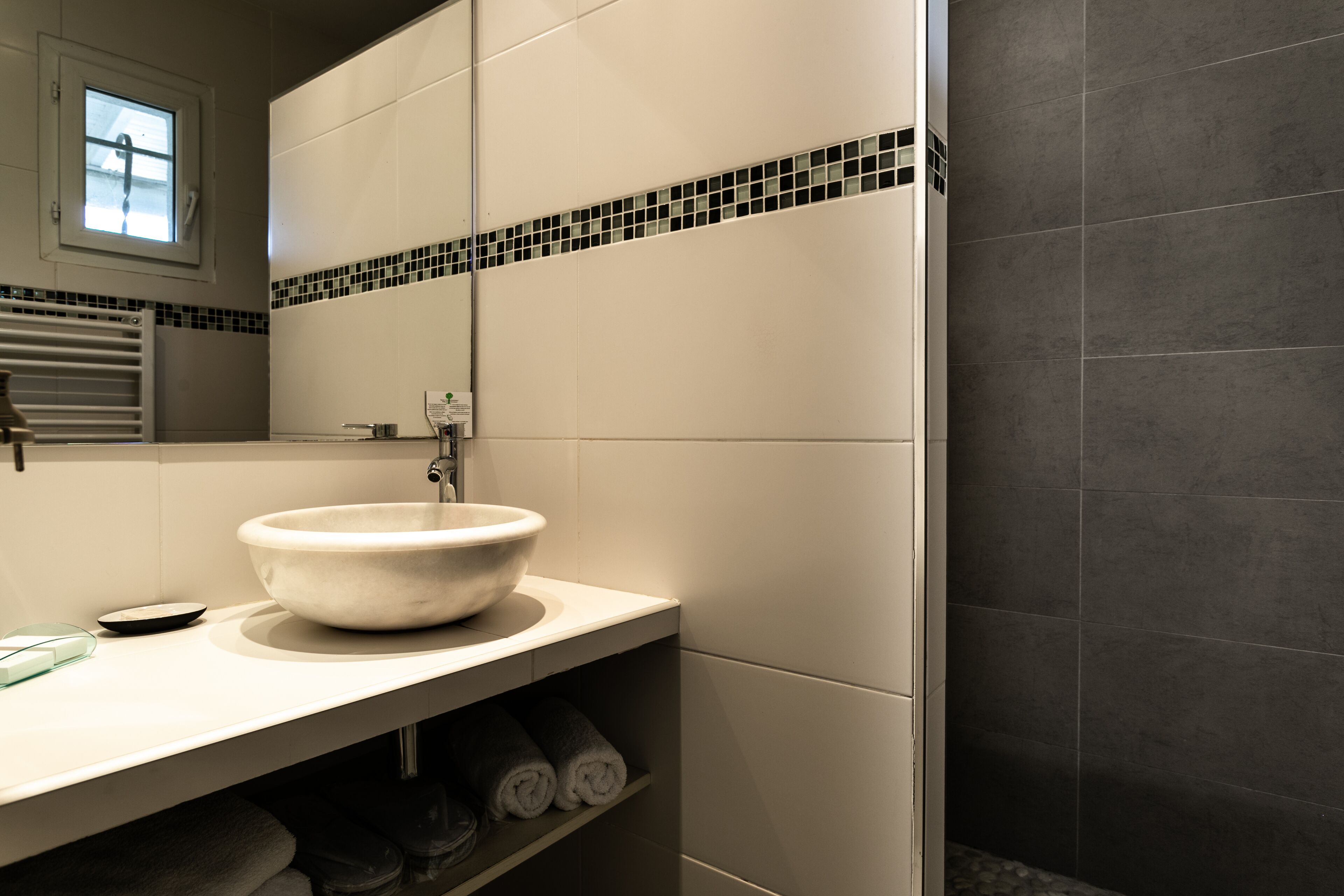 A bathroom with a large white sink, a mirror, and a tiled backsplash.