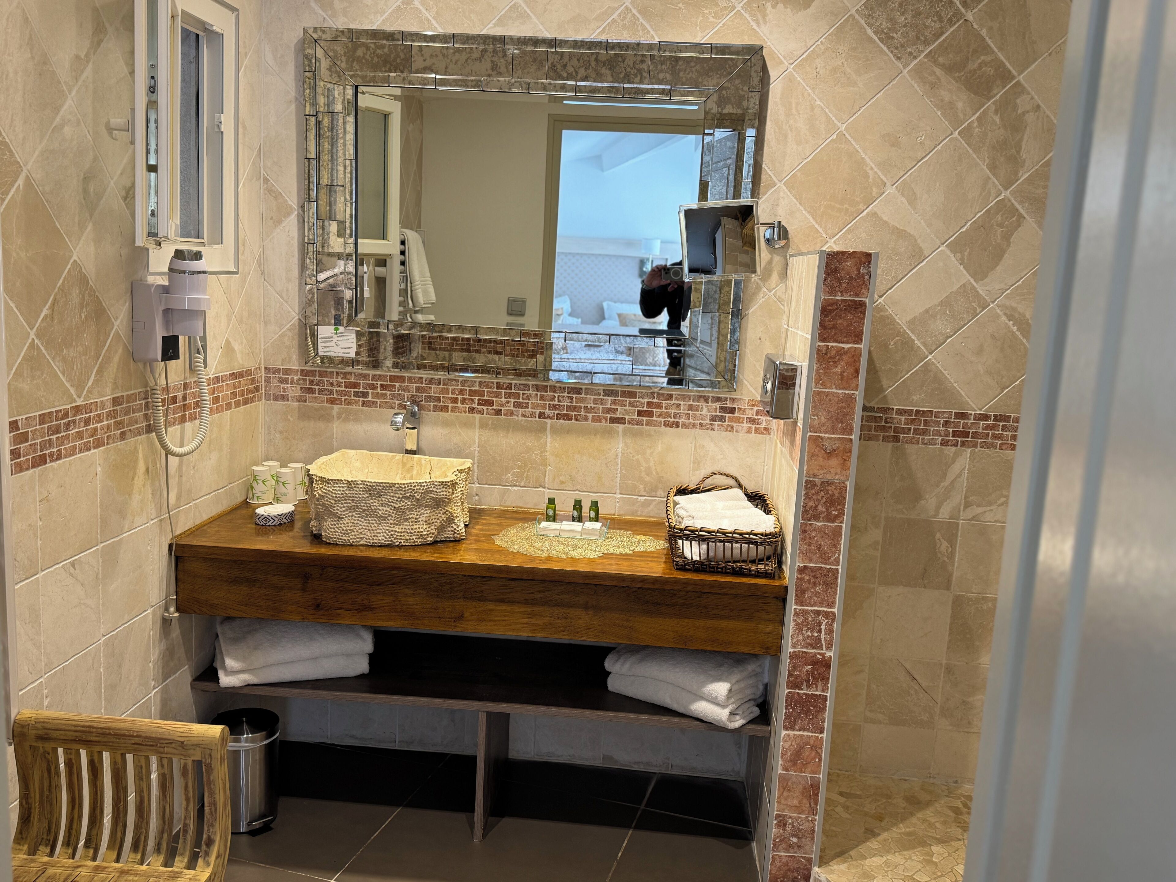 Un baño con tocador de madera, un lavamanos, un espejo y un perchero para toallas.