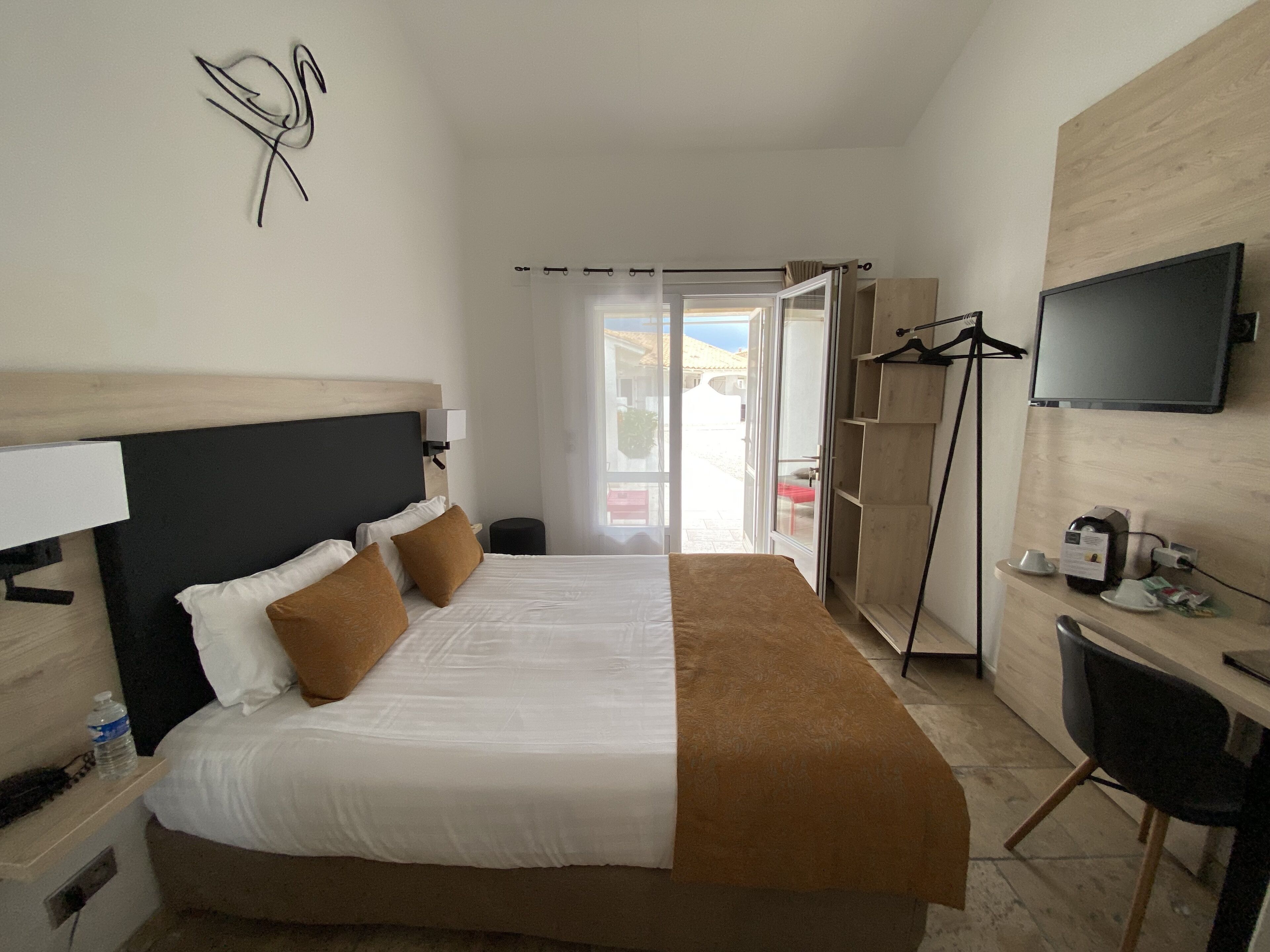 Una habitación de hotel con cama, escritorio, silla, televisor y armario.
