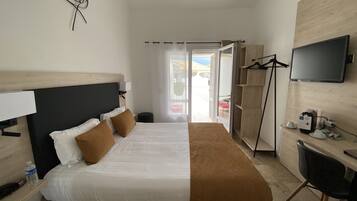 Una habitación de hotel con cama, escritorio, silla, televisor y armario.