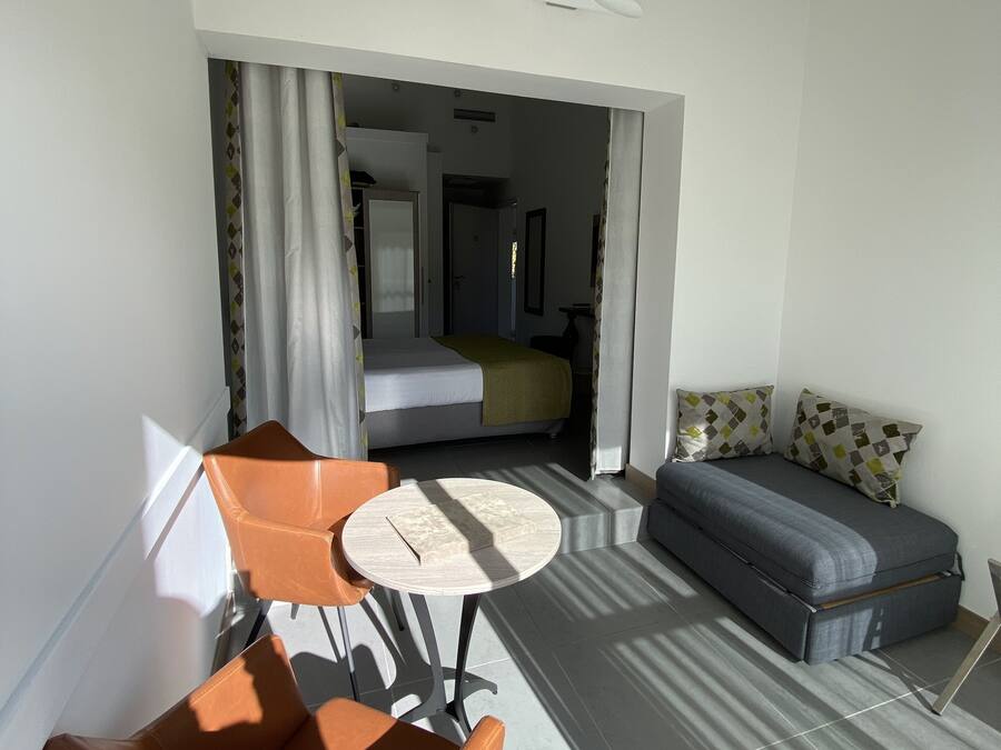 Una habitación moderna con una cama, un sofá, una mesita redonda y dos sillas.