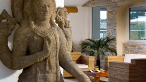 Uma escultura em pedra numa sala de estar com mobiliário de vime e vista para o exterior.