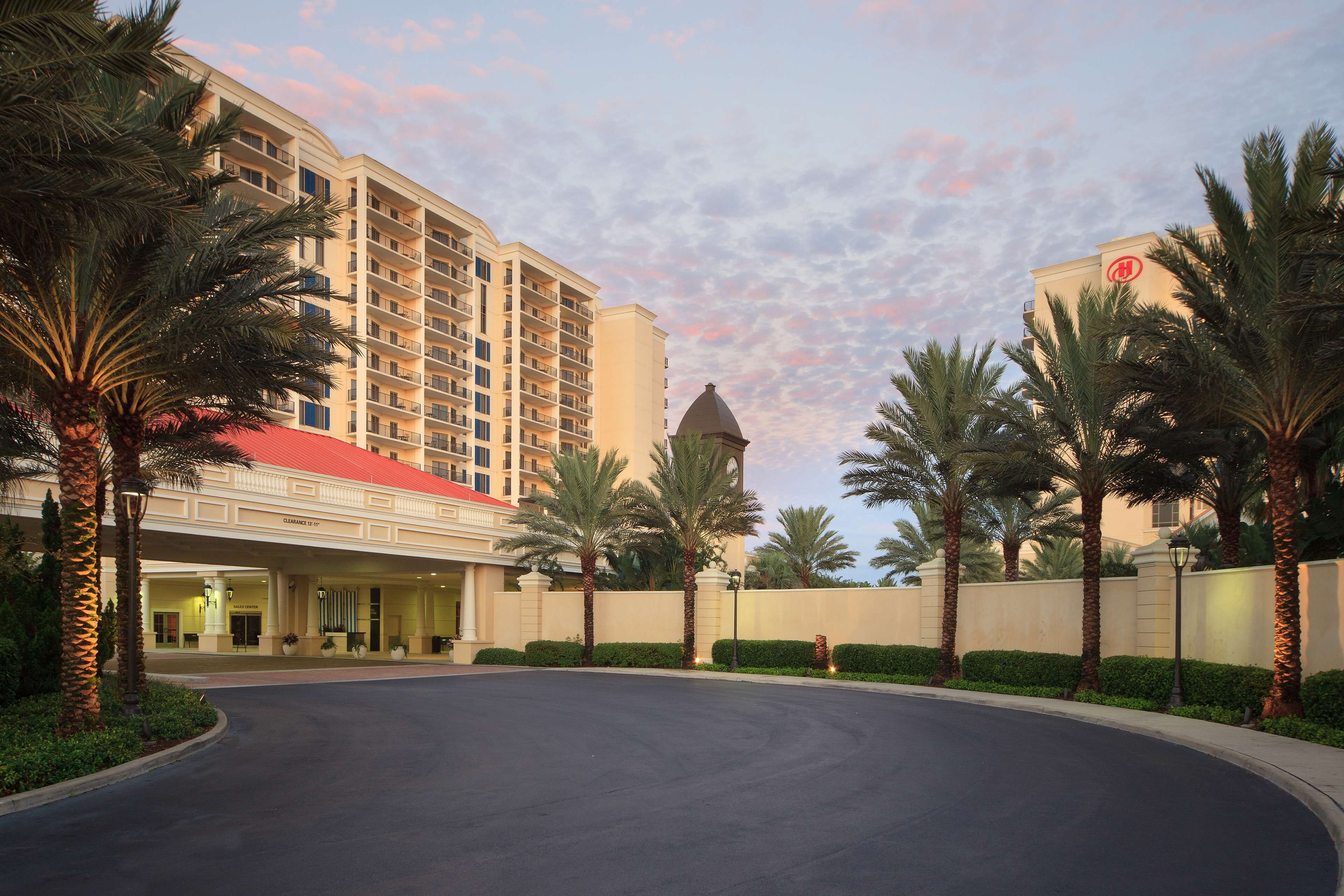 A hotel with a curved driveway, palm trees, and a building with a red roof.