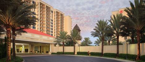A hotel with a curved driveway, palm trees, and a building with a red roof.