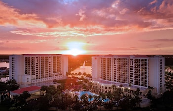 A modern living room with a sofa, coffee table, and a TV. There is a balcony with a view of the city. at Hilton Grand Vacations Club Parc Soleil Orlando