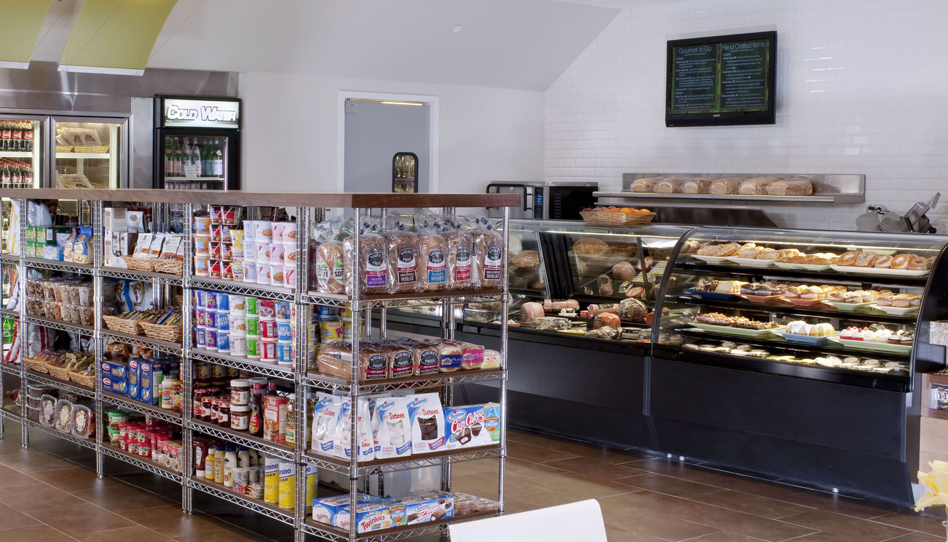 A bakery display with various baked goods and a refrigerated section with beverages.