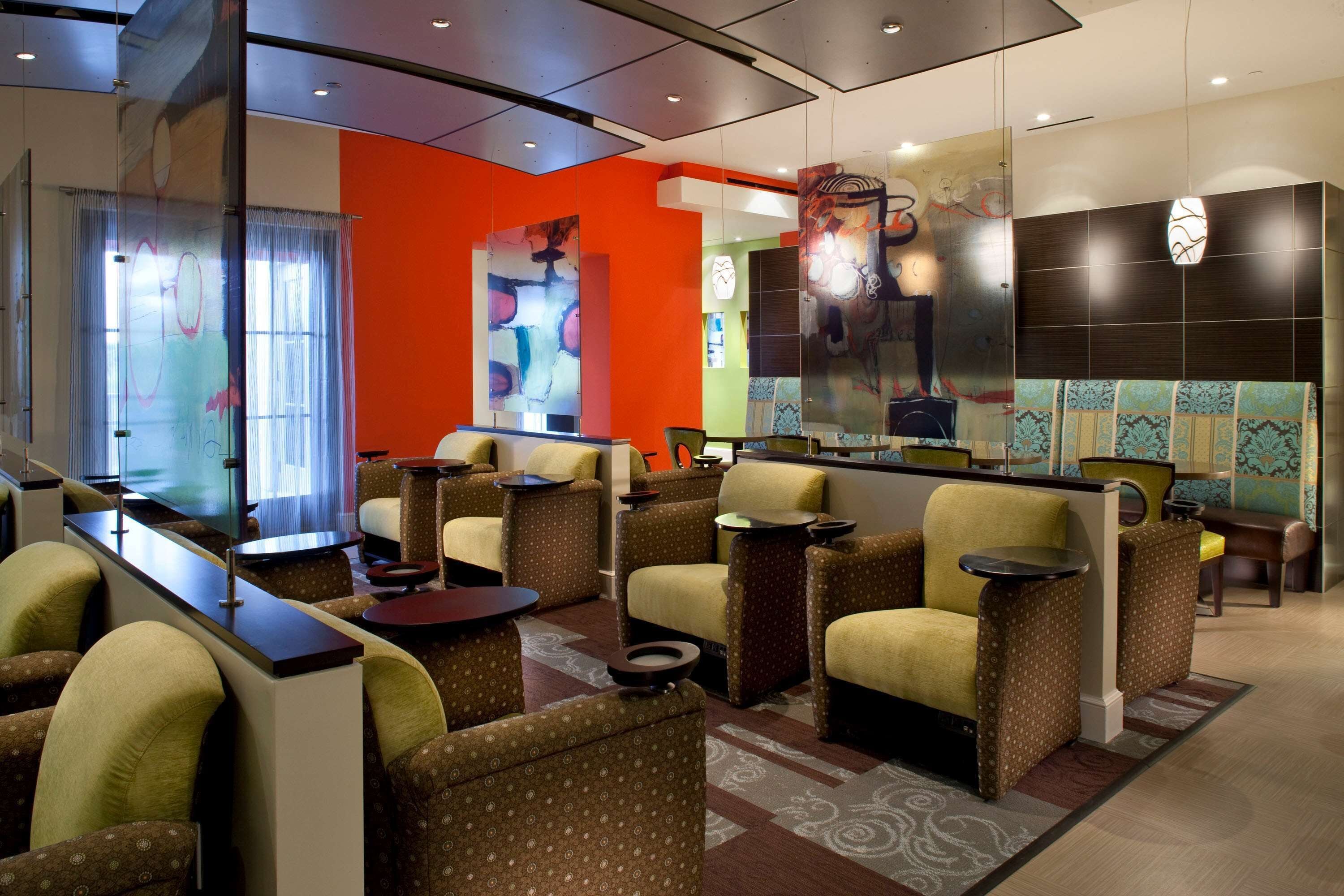 A lobby with seating areas, a reception desk, and a large abstract art piece on the wall.