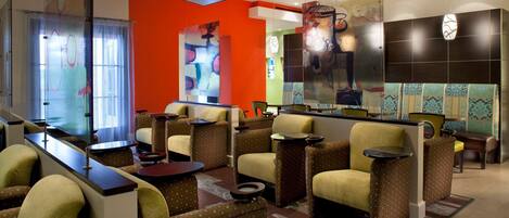 A lobby with seating areas, a reception desk, and a large abstract art piece on the wall.