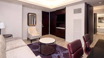 Una habitación de hotel moderna con sofá, sillón, mesa redonda y dos sillas de cuero.