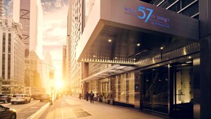 En modern hotellentrén med en tydlig skylt som visar texten ”West 57th Street by Hilton Club”.