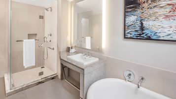 A modern bathroom with a glass-enclosed shower, a freestanding bathtub, and a large mirror above the sink.