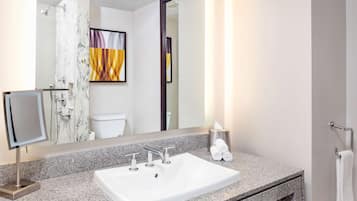 A modern bathroom with a large mirror, a white sink, and a towel rack.
