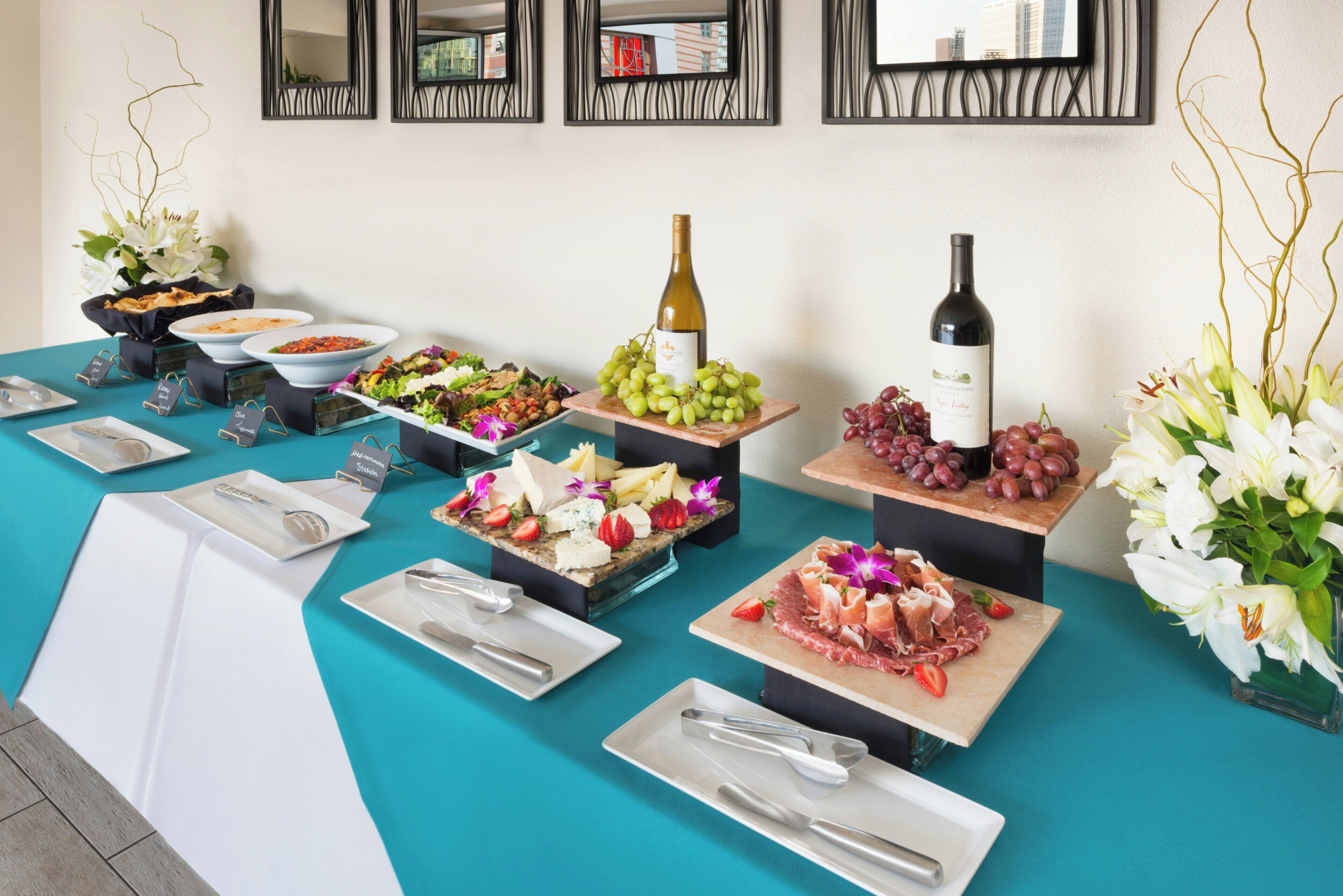 Una mesa de buffet con diversos alimentos y una botella de vino.
