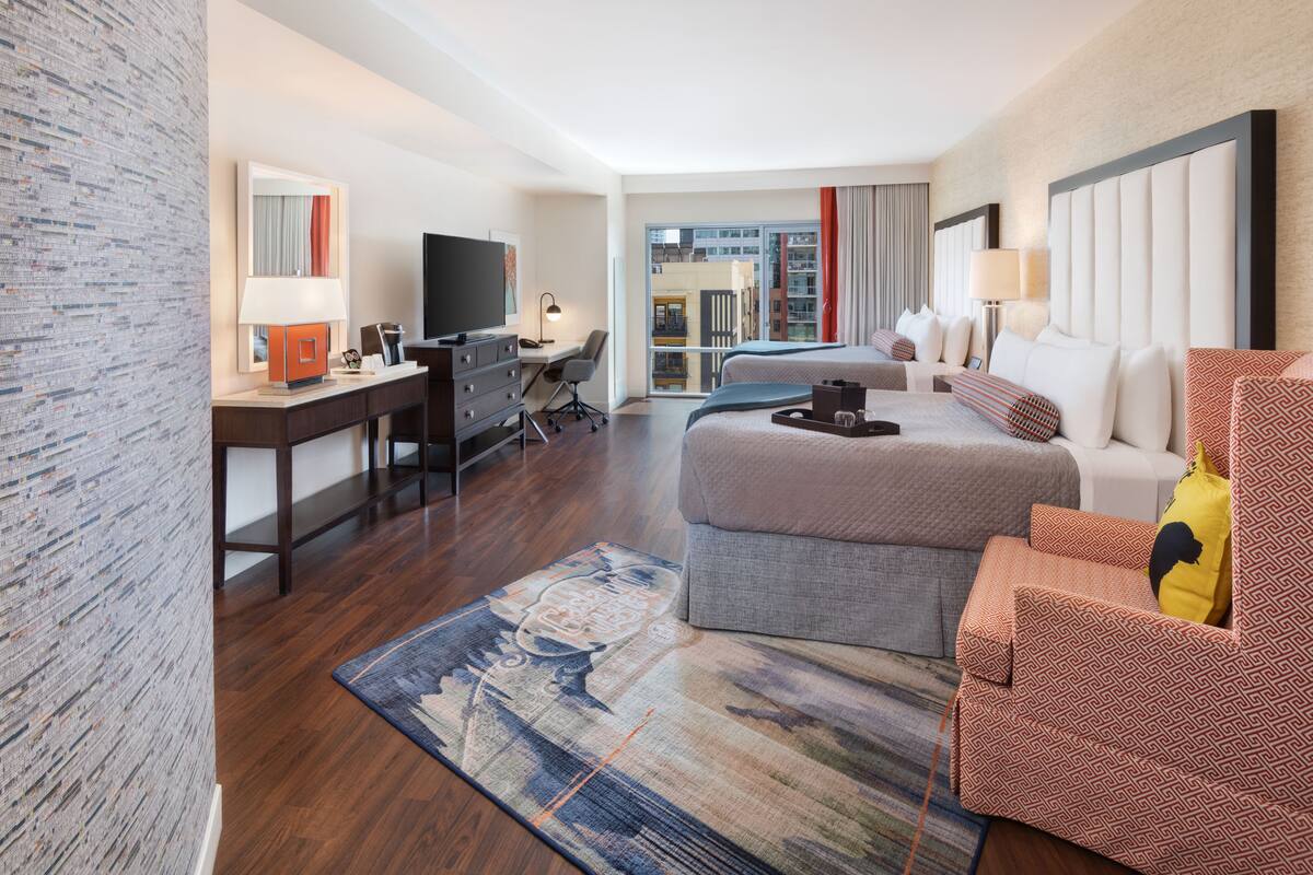 Une chambre d’hôtel équipée d’un lit, d’un bureau, d’une chaise, d’une télévision et offrant une vue sur la ville.