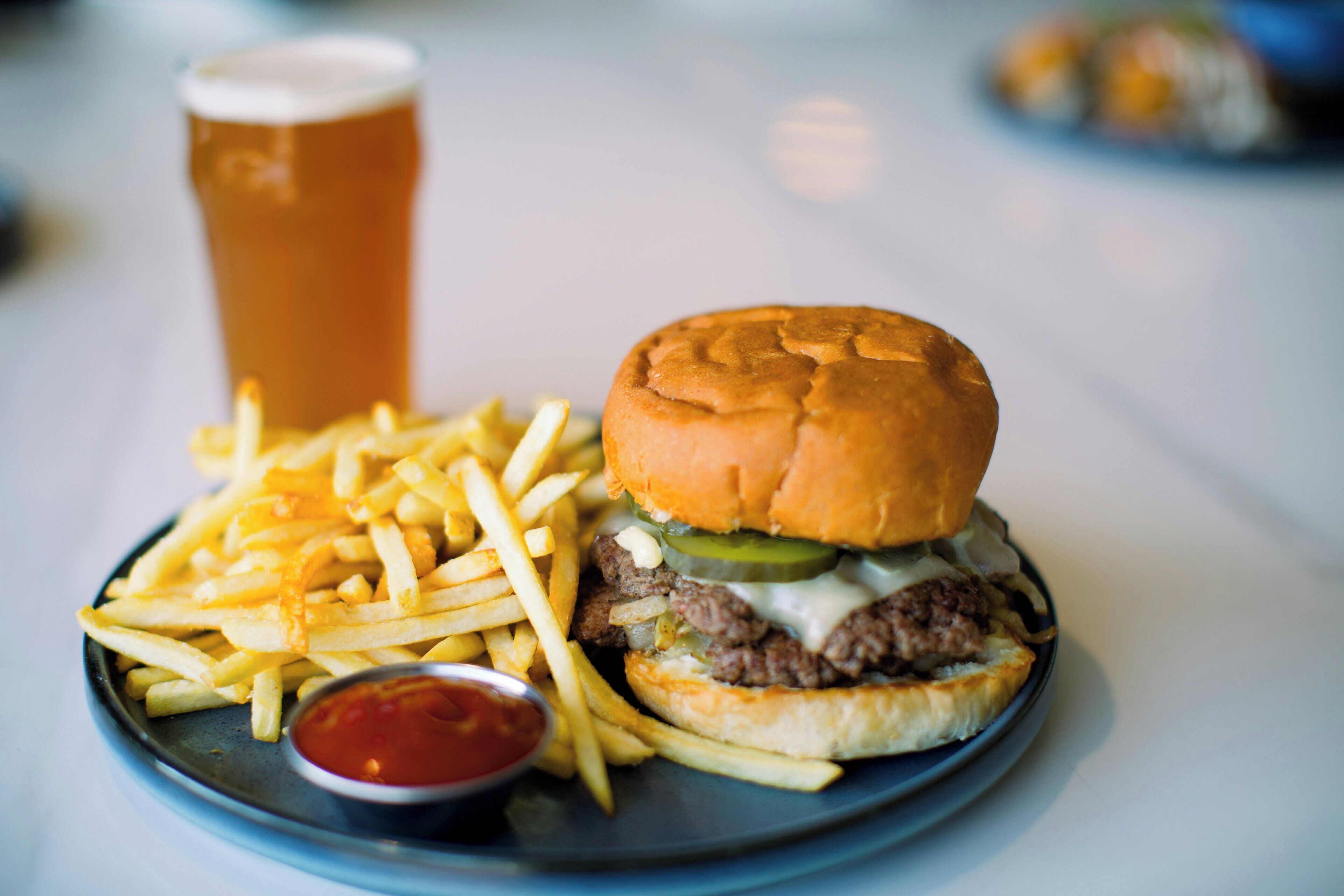 Un plato con una hamburguesa, papas fritas y una bebida.