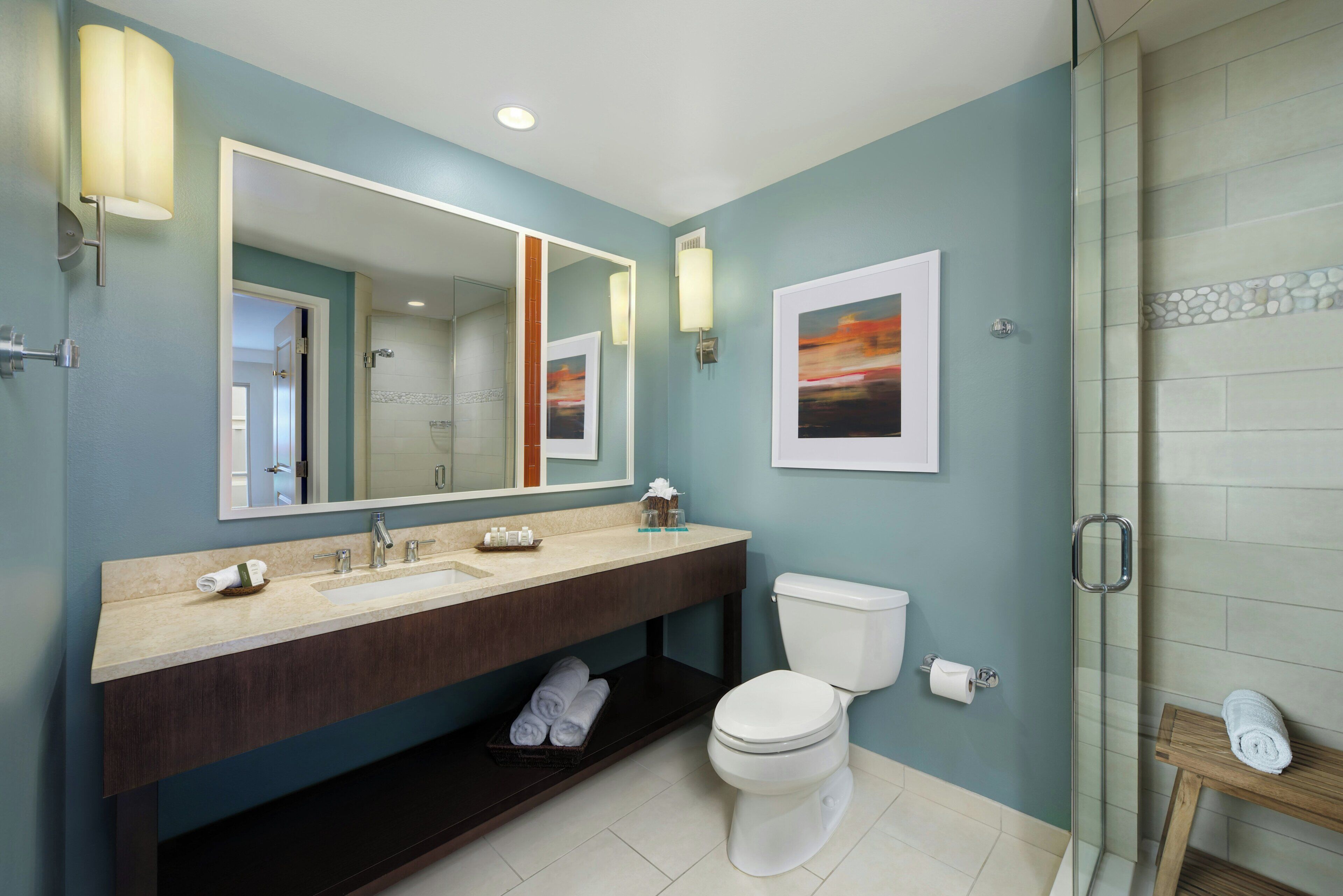 Un baño con un espejo grande, un lavabo con tocador, un inodoro y una zona de ducha.