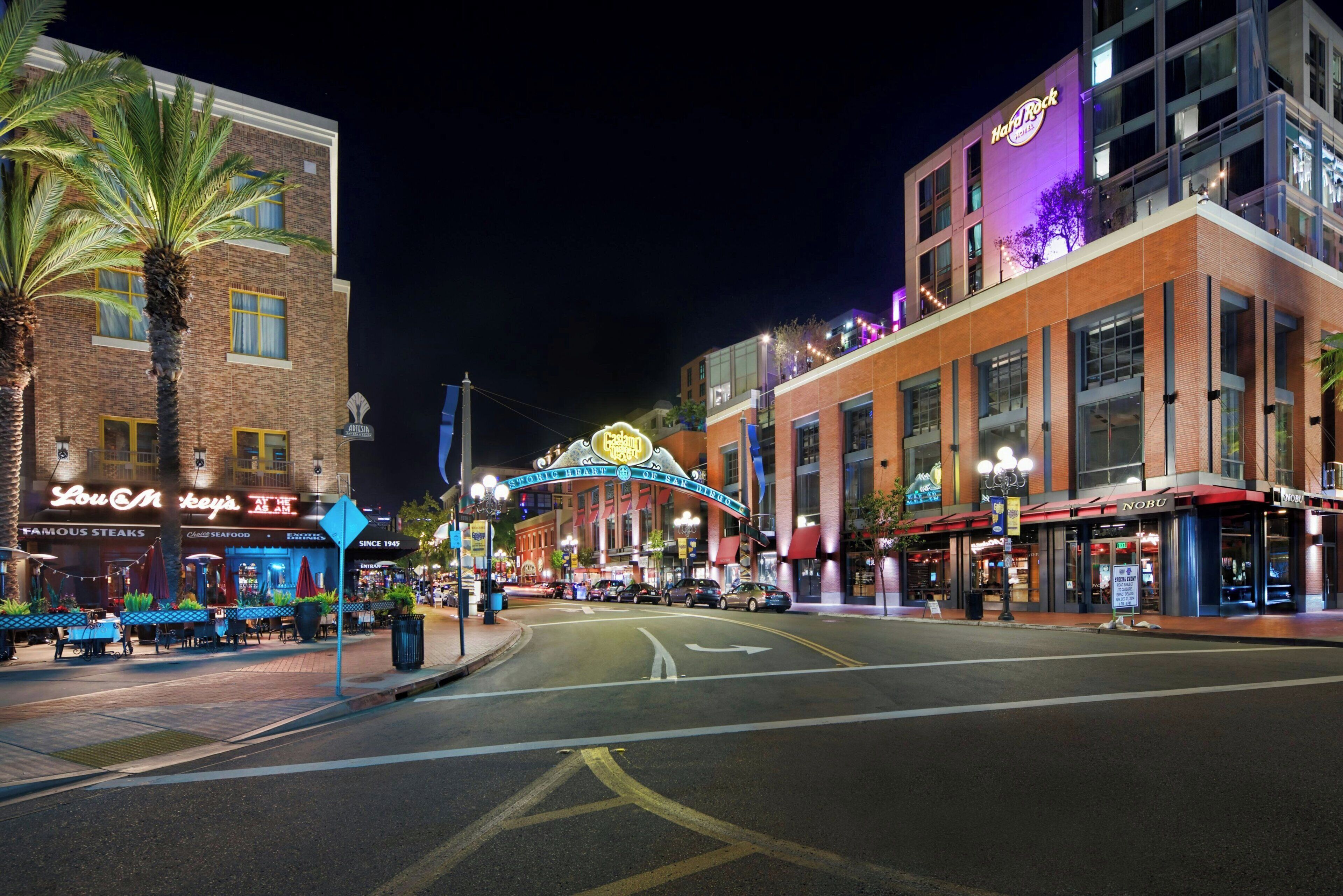 A street view at night with a variety of commercial buildings, including a Hard Rock Hotel and a restaurant named Lou & Mickey's.