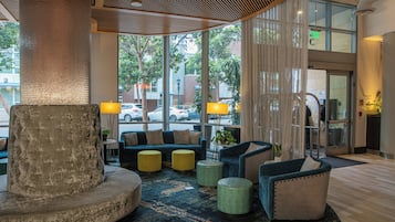 A lobby with a large pillar, seating area, and a view of the street through large windows.