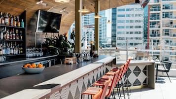 Zona de bar con una barra larga, distintas opciones de asientos y vistas a la ciudad.