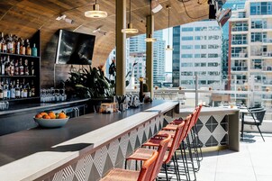 Un espace bar doté d’un long comptoir, de nombreux sièges et offrant une vue sur la ville.