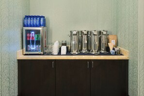 A bar area with a refrigerator stocked with beverages, coffee dispensers, and a bottle of sweet syrup. - Hotel Indigo San Diego-Gaslamp Quarter by IHG (San Diego)