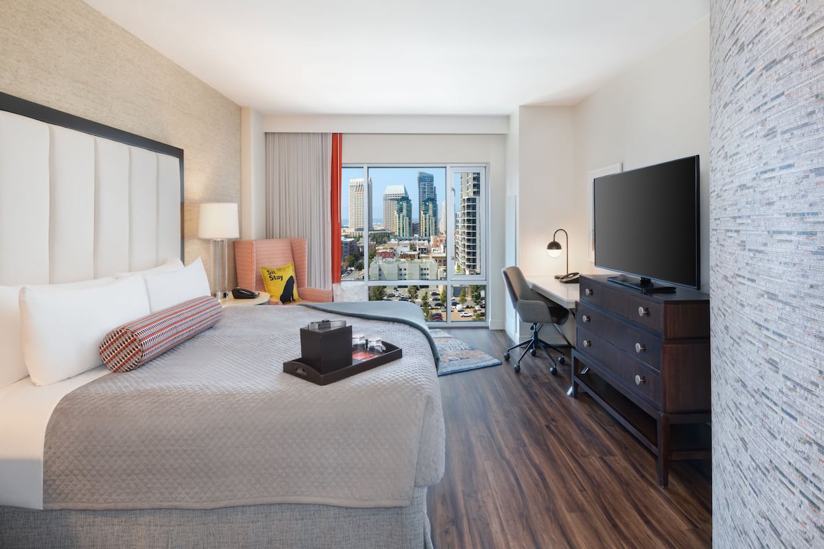 Une chambre d’hôtel avec un grand lit, un bureau, une télévision et une vue sur la ville.
