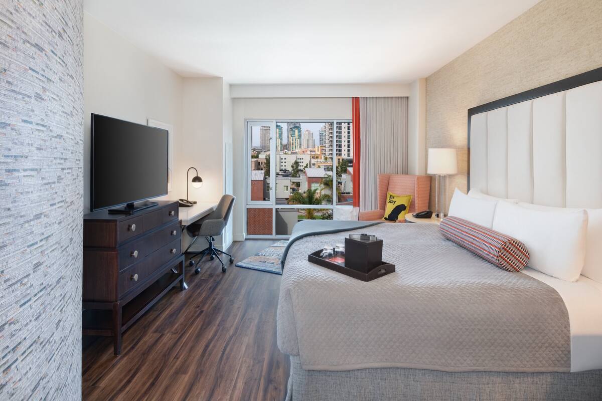 Une chambre d’hôtel avec un grand lit, un bureau, une télévision et une vue sur la ville.