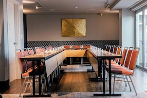 A conference room with a long table, multiple chairs, and a decorative wall piece.