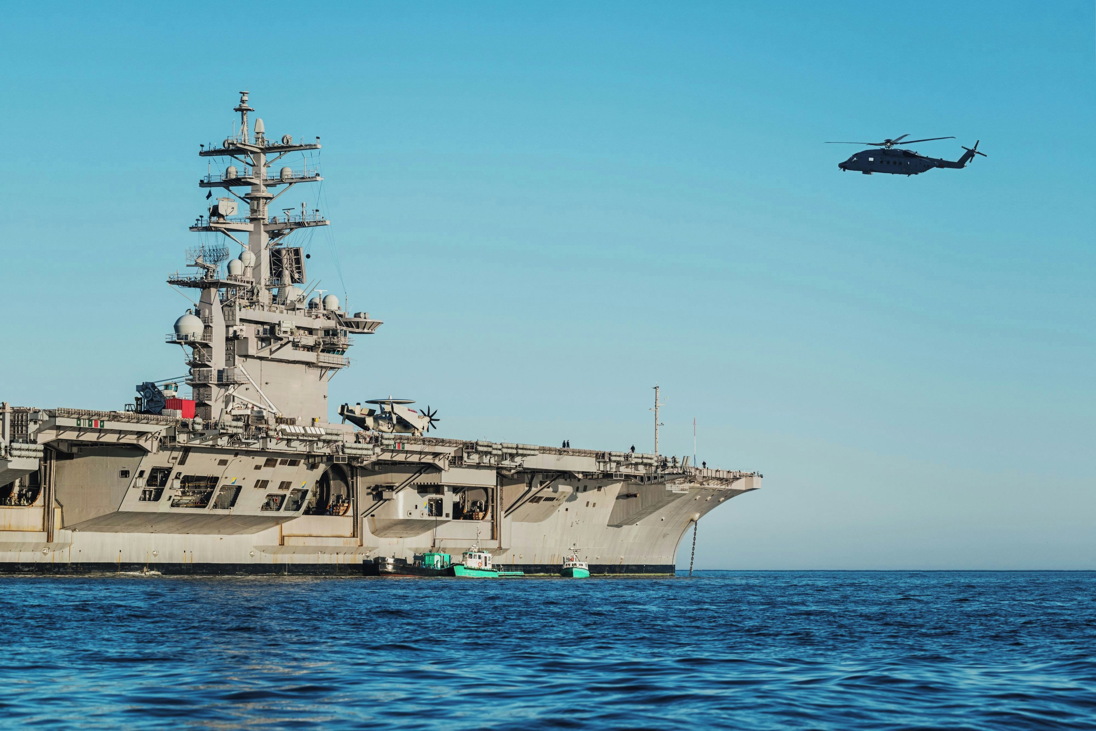 Een groot marineschip met een helikopter erboven.