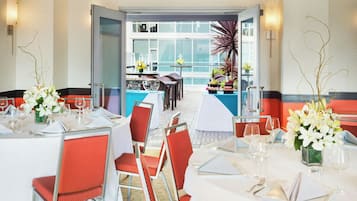 Ein Restaurant mit gedeckten Tischen, Stühlen und Blick auf die Straße durch große Fenster.
