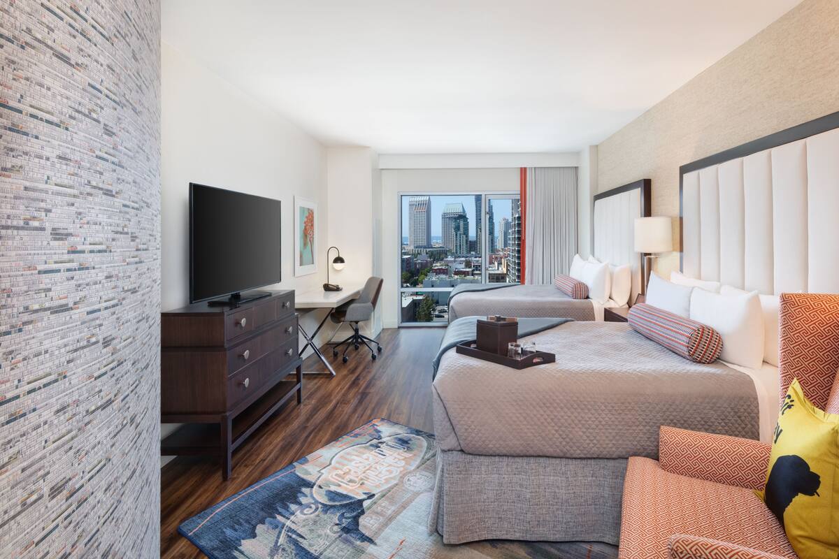 Une chambre d’hôtel moderne dotée d’un grand lit, d’un bureau, d’une télévision et offrant une vue sur la ville.