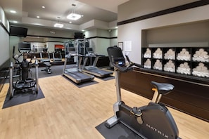 Un gimnasio con equipos de ejercicio variados, incluyendo cintas de correr, elípticas y una bicicleta estática.