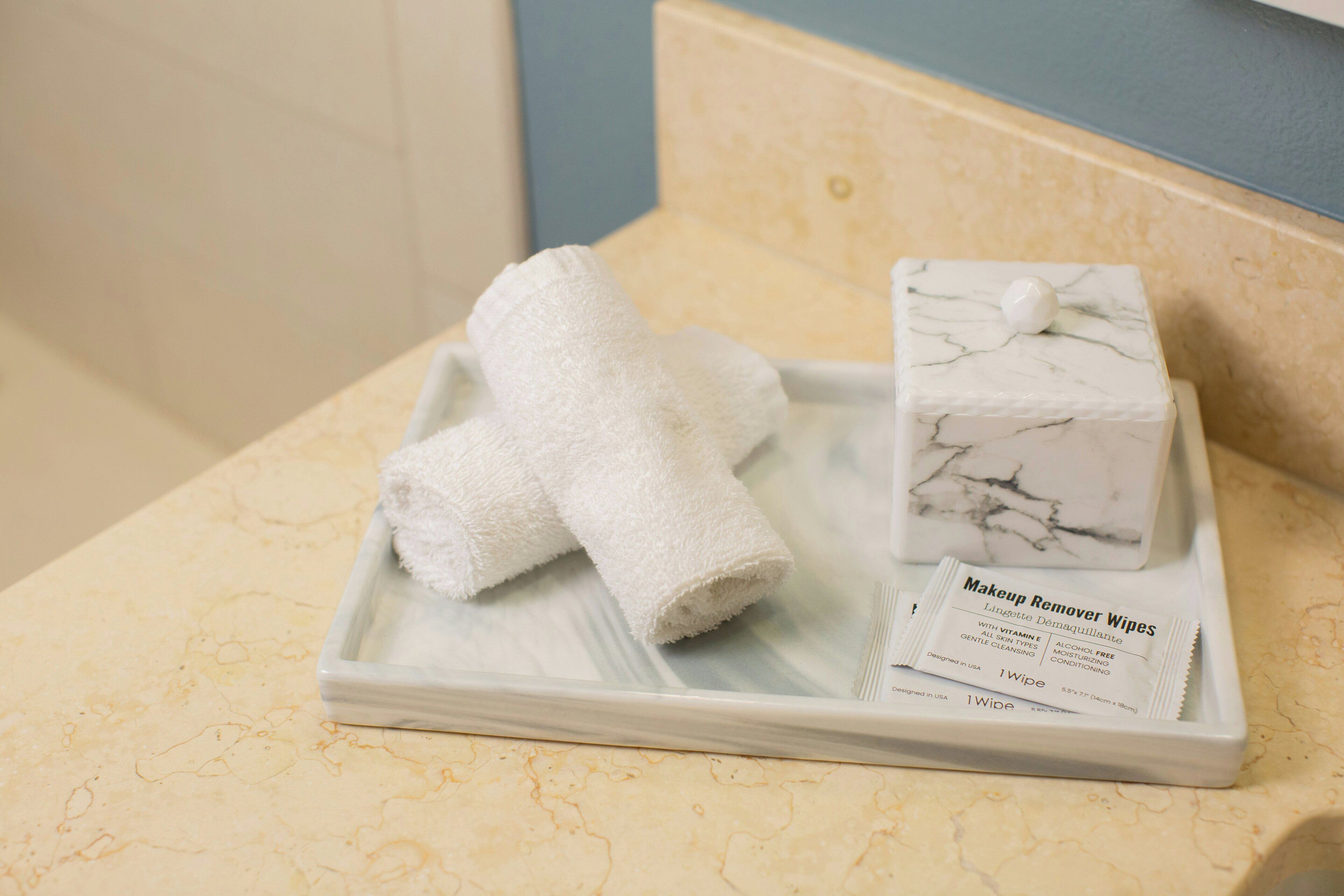A tray with two white towels and a marble soap on a bathroom counter.