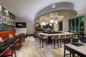 A modern bar area with a curved ceiling, bar stools, and a counter with a minibar. - Hotel Indigo San Diego-Gaslamp Quarter by IHG (San Diego)